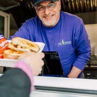 Chef Ted serving a Mr. Greens Chicken panini (Flamini) sandwich