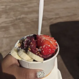 a hand holding a cup of fruit