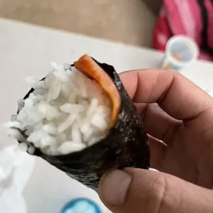 a hand holding a piece of sushi