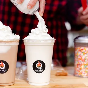 a person adding toppings to their drinks