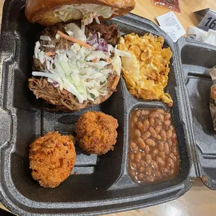 Pulled pork sandwich, cheese potatoes, baked beans and hush puppies.