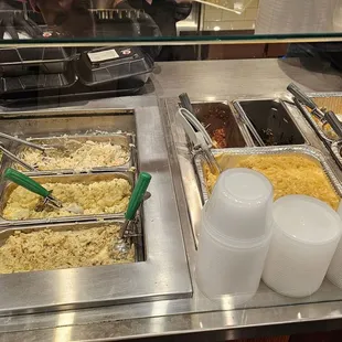 Food trays with mac n cheese, banana pudding, broccoli salad, potato salad, Coleman slaw, baked beans, greens, and more