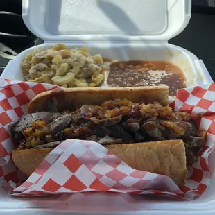 Tri tip sandwich with onions and bell peppers. Sides are Mac and cheese and baked beans.
