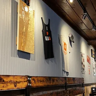 a wooden bench and a wall of shirts hanging on the wall