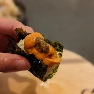 a hand holding a piece of sushi