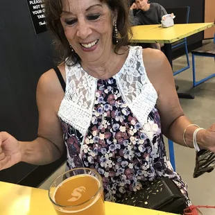 a woman sitting at a table with a glass of beer