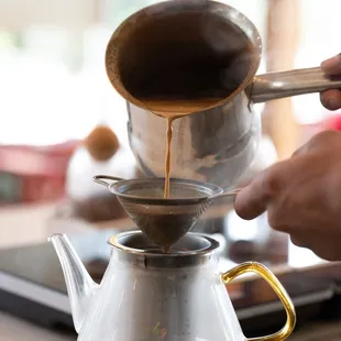 a person pouring coffee into a coffee pot