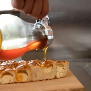 a person pouring syrup on a piece of bread