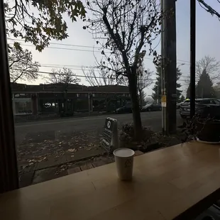 a cup of coffee on a table in front of a window