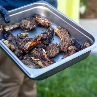 a person holding a tray of ribs