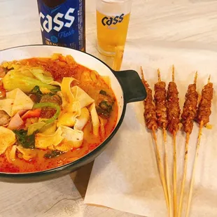 a bowl of soup and skewers