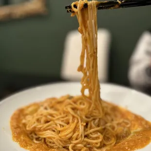 a plate of noodles with chopsticks
