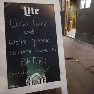 a chalk board with a sign saying we're here and we're beer