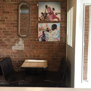 a table and chairs in front of a brick wall