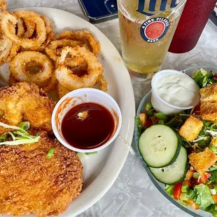 Deep fried chicken breast dinner with onion rings and side salad