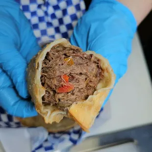 a person in blue gloves holding a sandwich