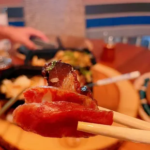 chopsticks holding a piece of meat