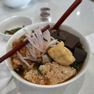 a bowl of soup with chopsticks