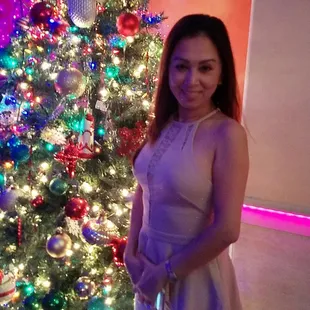 a woman standing in front of a christmas tree