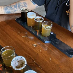 a man sitting at a table with a flight of beer