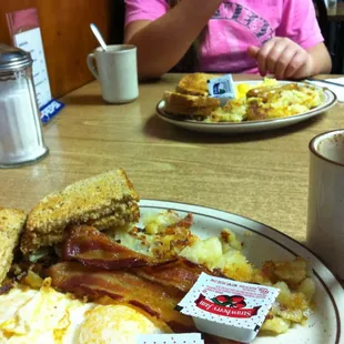 a breakfast plate with eggs, bacon and toast