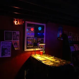 a dark room with a table and posters on the wall