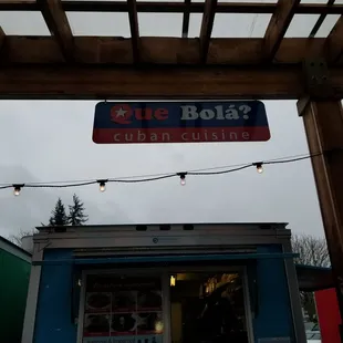 a blue bola's sign hanging from a pergol roof
