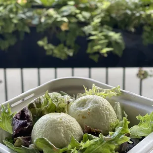 a hand holding a container of salad