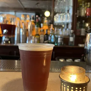 a drink in a plastic cup next to a candle