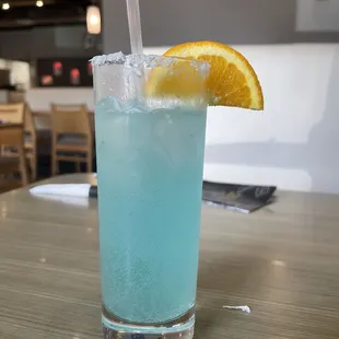 a blue drink with a slice of orange