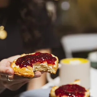 a person holding a piece of bread with jam on it