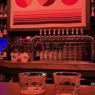 two glasses of beer on a bar