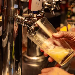 a person pouring a glass of beer