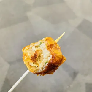 a person holding a piece of food on a stick