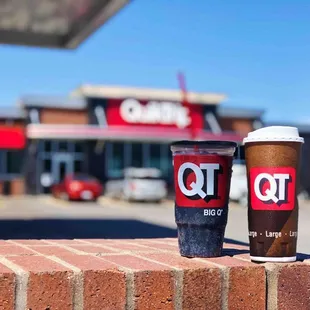 two cups of coffee sitting on a brick wall