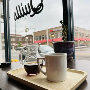 a cup of coffee and a pitcher on a tray