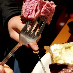 a person holding a fork over a plate of food