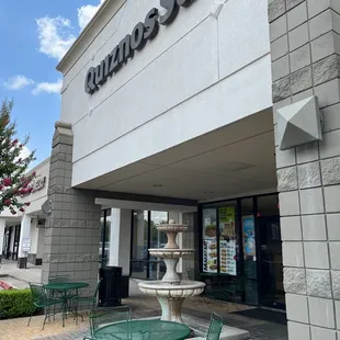 the outside of a restaurant with tables and chairs