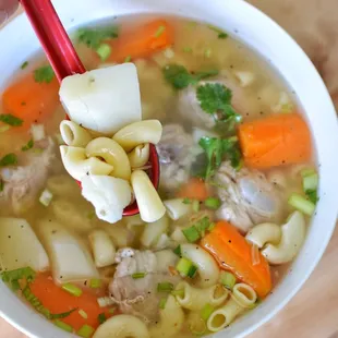 Macaroni soup featuring pork riblets, potatoes, and carrots, topped with green onions and cilantro, creates a heart-warming meal