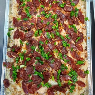 Sticky rice accompanied by chicken and Chinese sausage, garnished with crispy fried onions and fresh green onions.