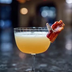 a cocktail with bacon garnish