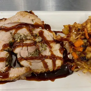 Porchetta with fennel demi and local roasted vegetables in a potato nest