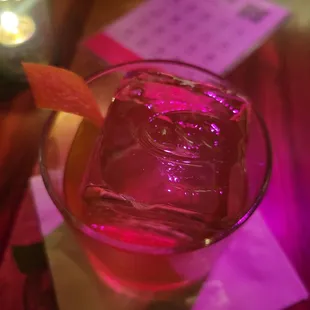 a glass of pink liquid with an orange slice