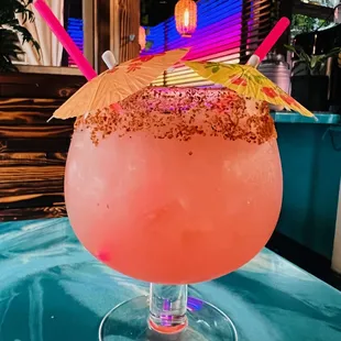 a pink cocktail with an umbrella