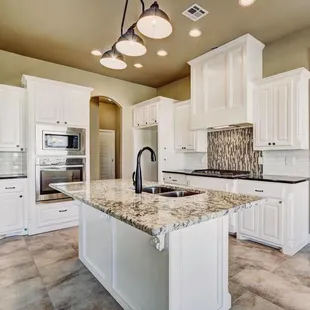 a kitchen with white cabinets and granite countertops