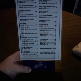 a hand holding a beer list