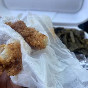 a hand holding a piece of fried chicken
