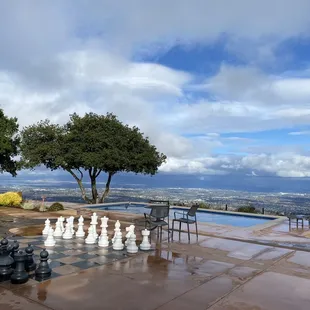 a large chess set on a patio overlooking a pool