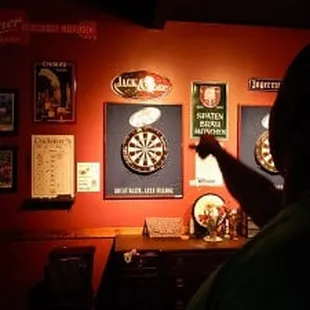 a man pointing at a dart on a wall