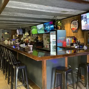 a bar with stools and televisions